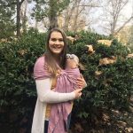 woman wearing baby in a ring sling carrier