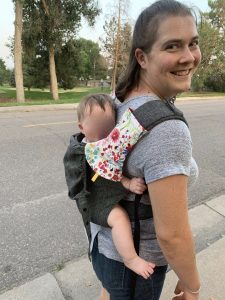 Action shot of woman wearing baby on her back in a structured carrier 