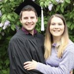 Married couple standing in front of the lilac bush